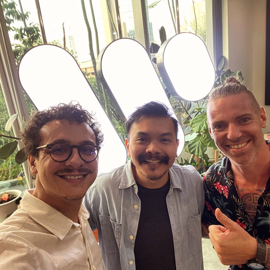three man standing in front of music label logo Warner Music